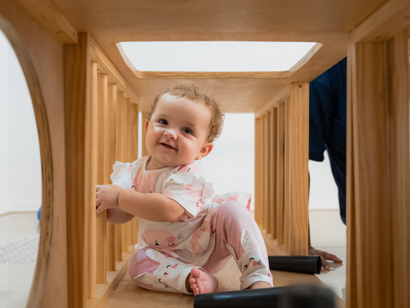 Uma menina brincando em uma estrutura de madeira para brincar.