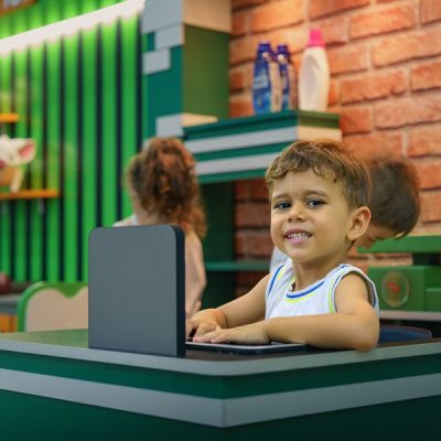 Um jovem menino sentado em uma mesa com um laptop.