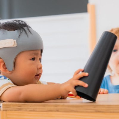 Duas crianças brincando com um brinquedo em cima de uma mesa.